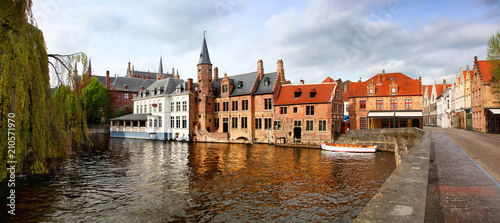 Panoramic of the charming and colorful buildings and bridges of Bruges reflecting on the water of the canal