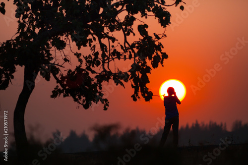 Fototapeta Naklejka Na Ścianę i Meble -  A silhouette tree beside people with sunset under colorful of sky 