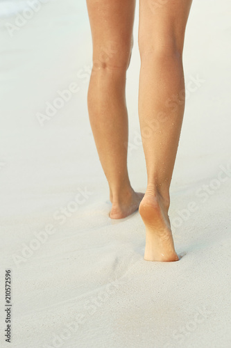 Сlose up of woman leg on the beach. Woman feet walking on the sand. Foot female.Skin Care.