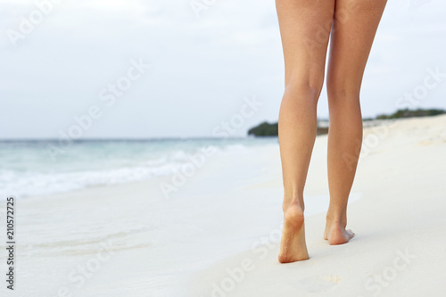 Woman walking on sand beach leaving footprints in the sand. Сlose up of woman leg on the beach.Feet female