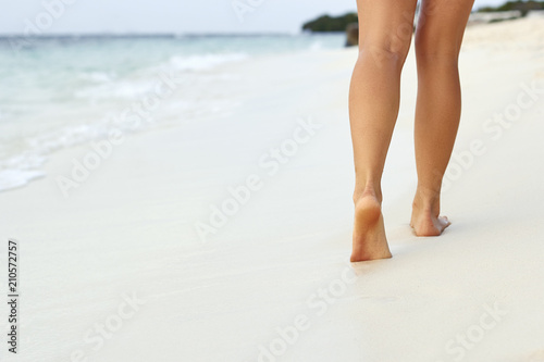 Woman walking on sand beach leaving footprints in the sand. Сlose up of woman leg on the beach.Feet female