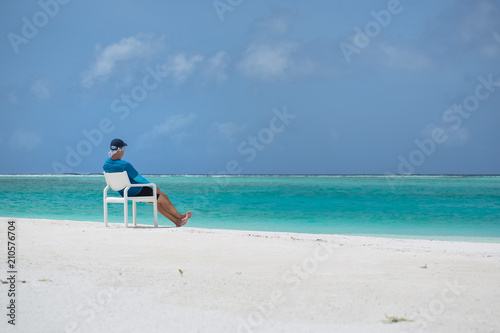 A man sits on a chair on the beach and looks out to sea © Bianca Regner