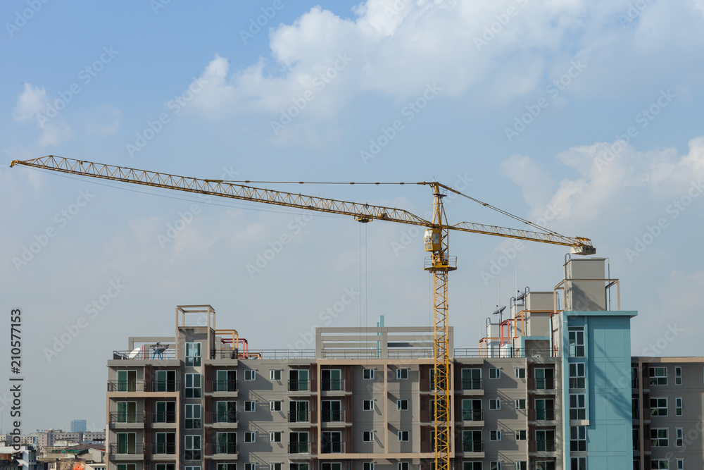 construction site of building condominium with crane above by cloudy 