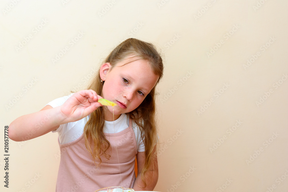 Close up portrait of funny lovely caucasian little girl eat apple with honey indoor. Jewish child dipping apple slices into honey on Rosh HaShanah the Jewish New Year.