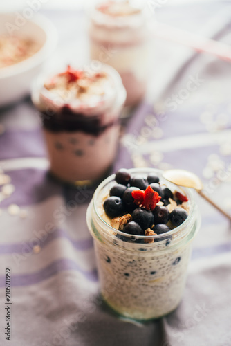 Vanilla chia parfait on a glass mason jarr topped with blueberres, shallow depth of field, selective focus technique.