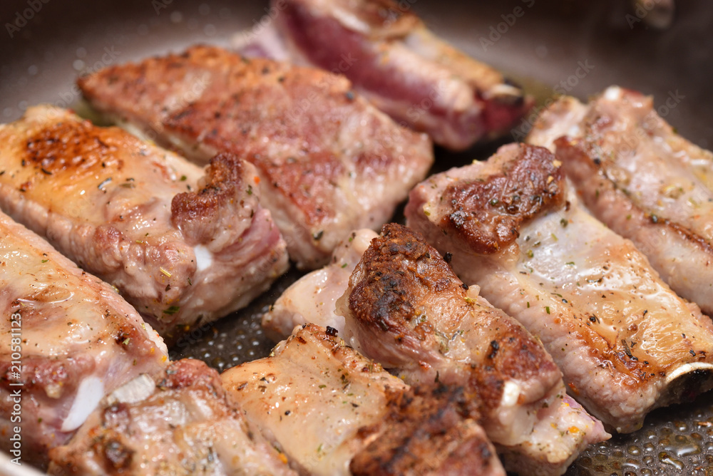 Beautiful and ruddy pork ribs are fried in a frying pan. Close-up