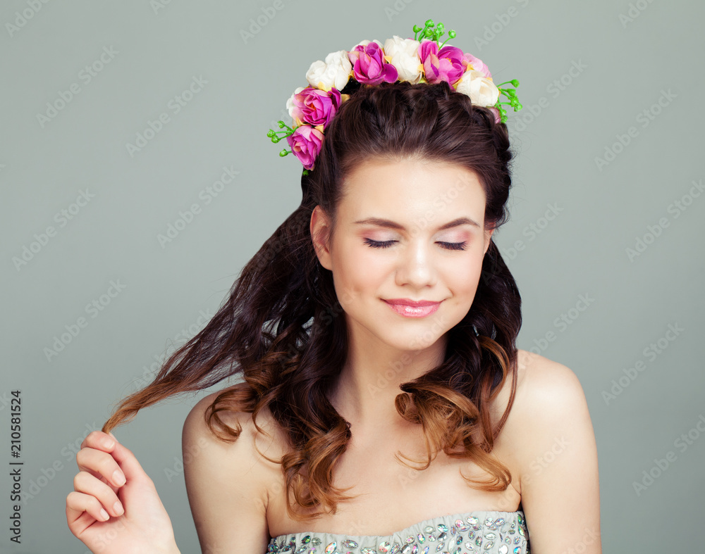 Cute Woman with Perfect Hairstyle and Makeup on Grey Background. Young Female Model with Flowers in Hair