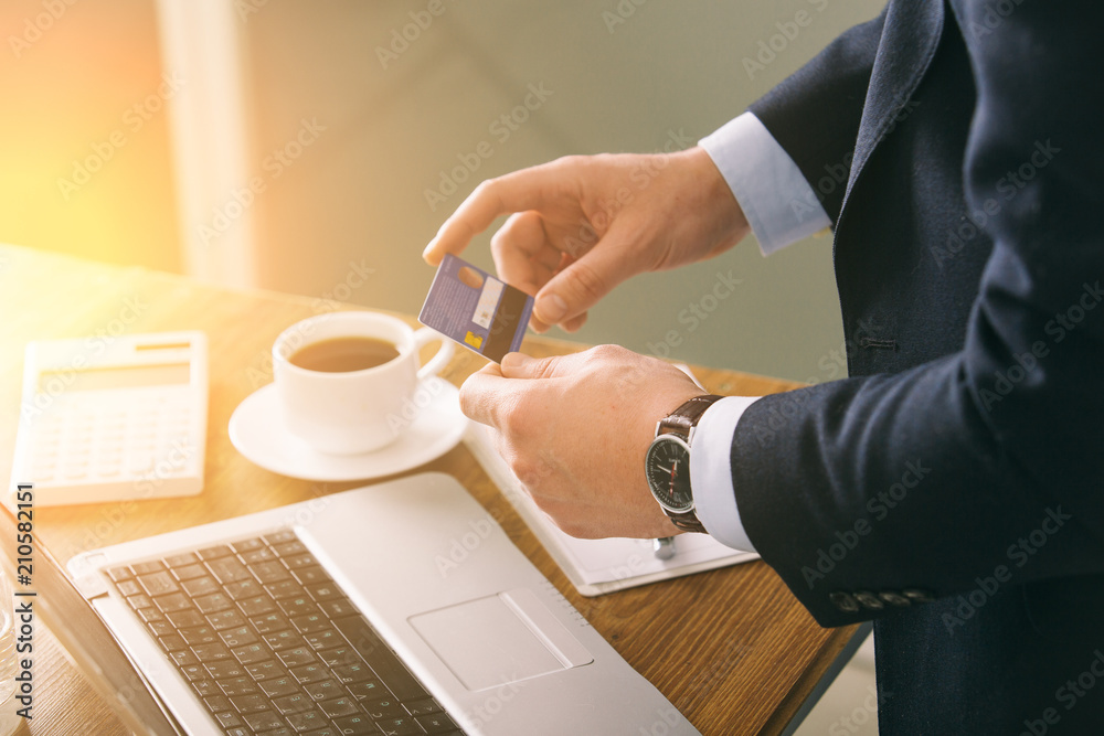 young businessman in dark office with smartphone tablet and credit card