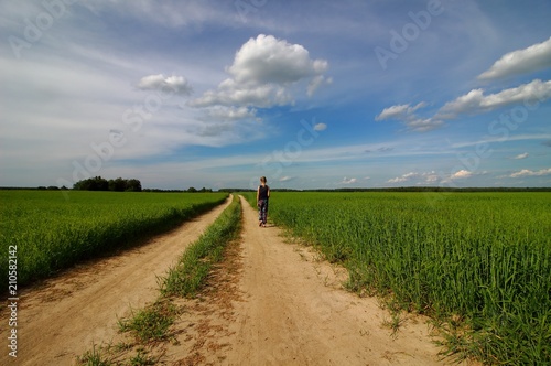 The girl is walking on the road in the field, summer. © Jekaterina