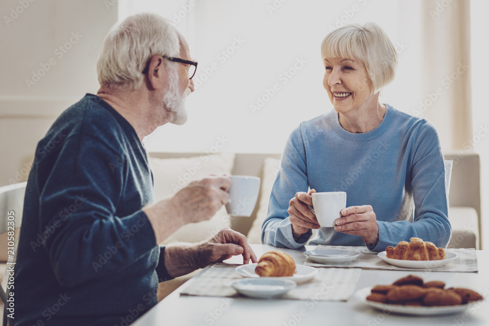 Positive mood. Joyful aged people smiling to each other while enjoying their meal Positive mood. Joyful aged people smiling to each other while enjoying their meal