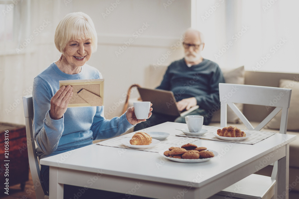My youth. Positive joyful woman looking at the photo while remembering her youth My youth. Positive joyful woman looking at the photo while remembering her youth