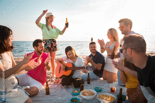 Multicultural group of friends partying on the beach – happy young people celebrating during summer vacation, summer time and holidays concepts.