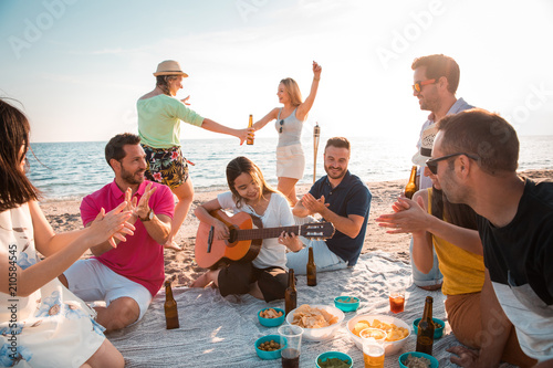 Multicultural group of friends partying on the beach – happy young people celebrating during summer vacation, summer time and holidays concepts. photo