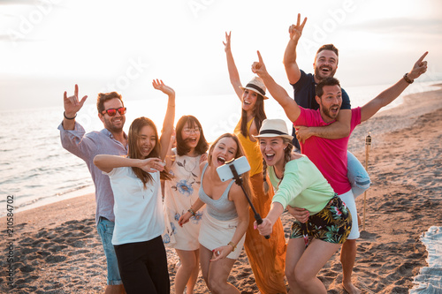 Happy multiracial young people are making a selfie at the beach while they are in a summer party. Friends and holiday concept