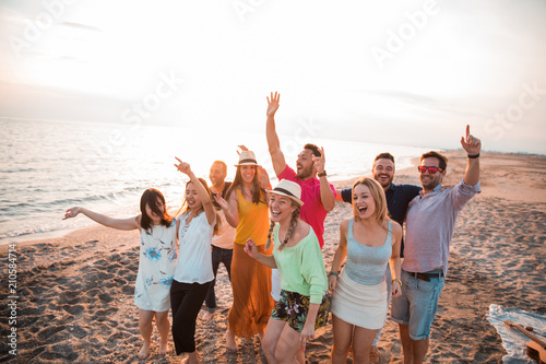 Happy multiracial young people are dancing at the beach in a summer party. Friends and holiday concept