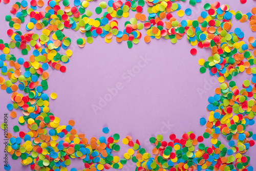 Frame made of colored confetti. Lilac and violet background.