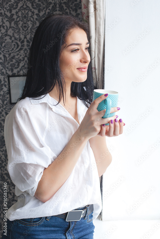 Young attractive woman drinking tea or coffee at her kitchen. Lady indors relaxing with cup of hot drink Young attractive woman drinking tea or coffee at her kitchen. Lady indors relaxing with cup of hot drink
