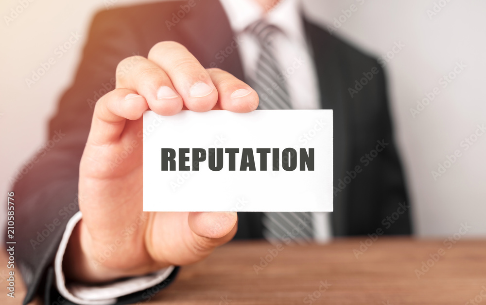 Businessman holding a card with text Reputation Businessman holding a card with text Reputation
