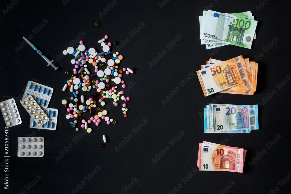 Money and pills. Pills of different colors on black background.