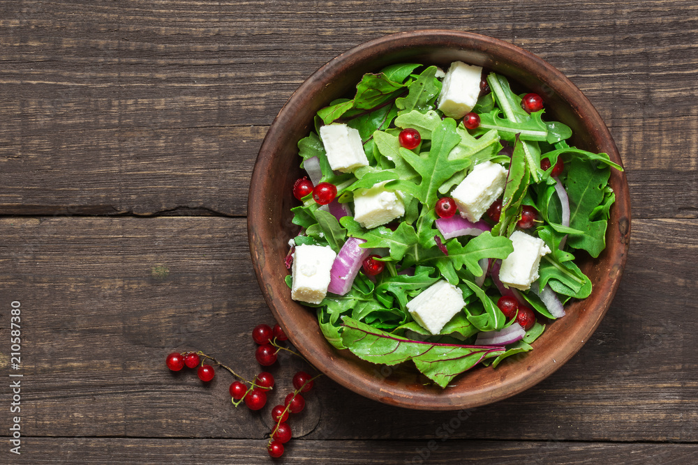 Fresh salad with rucola, mesclun, feta cheese, red onion and red currant in a bowl on rustic wooden table. top view Fresh salad with rucola, mesclun, feta cheese, red onion and red currant in a bowl on rustic wooden table. top view