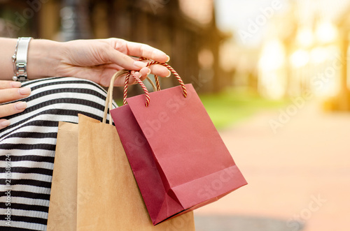 A woman is holding a gift package bag in hand shopping on blur nature sun background