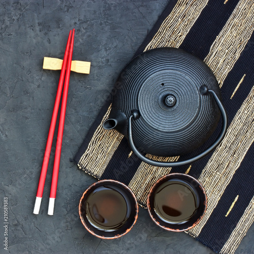 Black teapot and tea cups on stone table. Top view with copy space