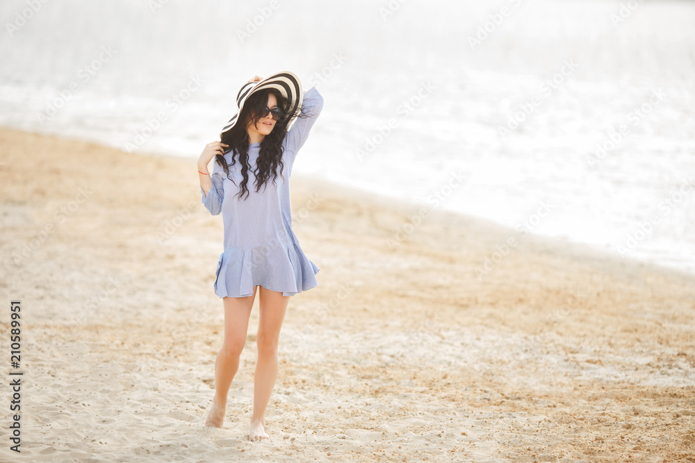 Young pretty woman walking on a beach. Attractive adult girl near the water relaxing. Beautiful woman on the sea Young pretty woman walking on a beach. Attractive adult girl near the water relaxing. Beautiful woman on the sea