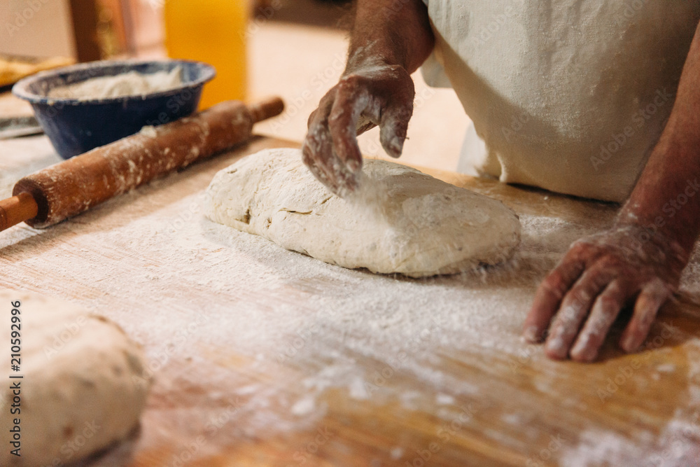 Male baker prepares bread. Baker kneading the dough with flour. Making bread. Rustic and traditional style of Bakery. Male baker prepares bread. Baker kneading the dough with flour. Making bread. Rustic and traditional style of Bakery.