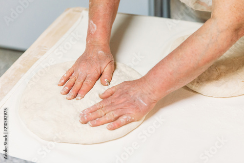 Baker is preparing dough for pizza in a traditional Bakery.