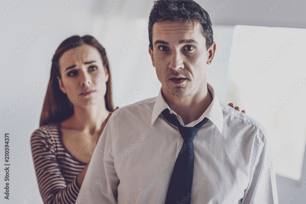 Problems in relationships. Depressed nice man standing in front of his wife while thinking about problems Problems in relationships. Depressed nice man standing in front of his wife while thinking about problems
