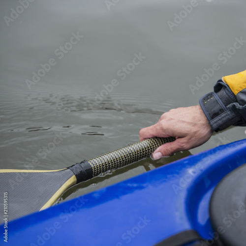 man in a kayak sports boat pushes an oar into the water, close-up.