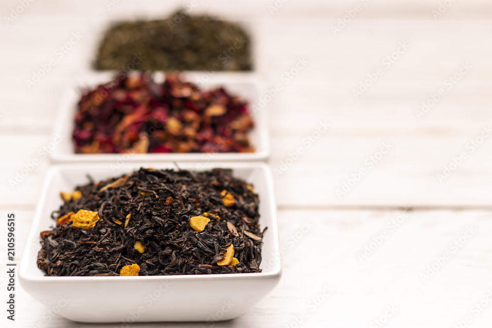 Close-up view of dry tea leaf in white scoops stand in row on white wooden table Close-up view of dry tea leaf in white scoops stand in row on white wooden table