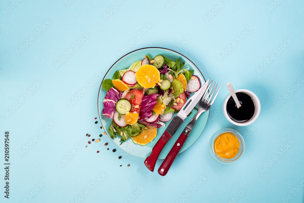 Fresh vegetables salad with various dressing on blue background, top view, border. Fresh vegetables salad with various dressing on blue background, top view, border.