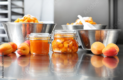 Jam from apricots in a glass jar on a polished stainless steel surface in pastry worktop