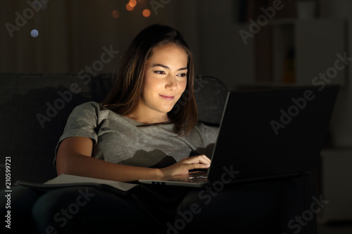 Woman using a laptop in the night on a couch