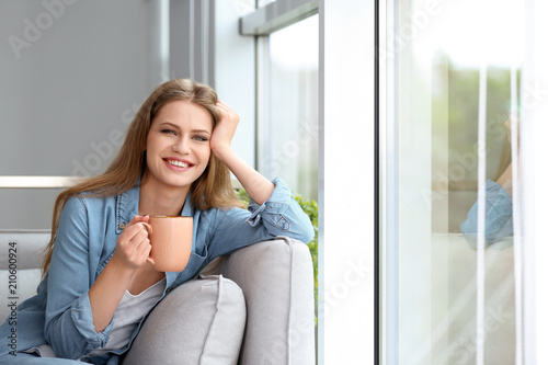 Young beautiful woman drinking morning coffee near window at home Free Download Young beautiful woman drinking morning coffee near window at home - GFXLoad