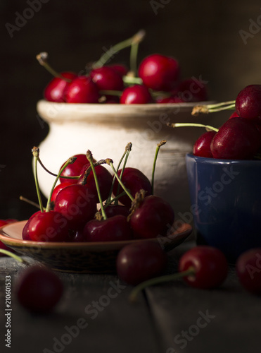 still life picture in the dark of fresh cherry on plate on wooden black background. fresh ripe cherries. soft focus image  © RomanWhale studio