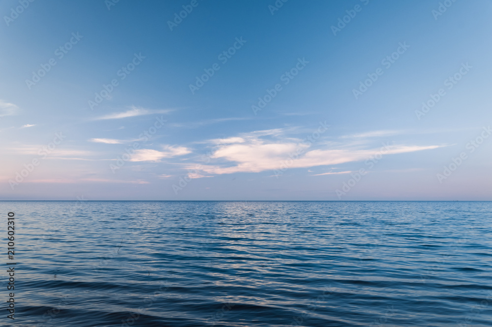 Clouds over blue sea waves. Sky reflecting in water. Ladoga lake.