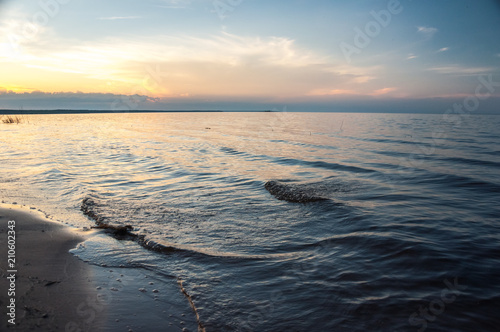 Sea waves on the sandy beach in sunset. Ladoga lake