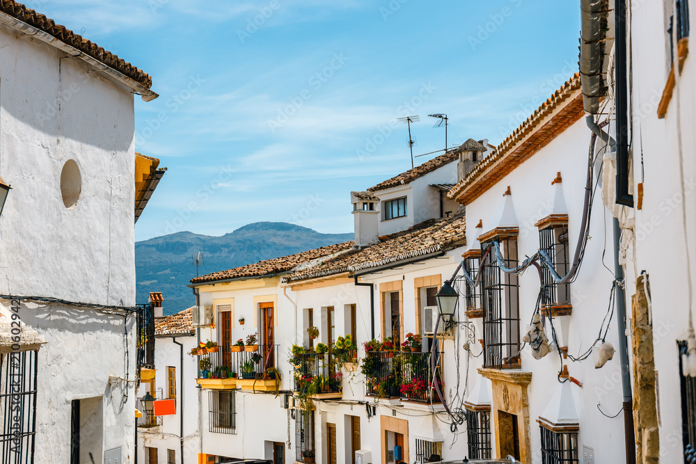 narrow street with white facades of houses in historic district of Ronda, Spain