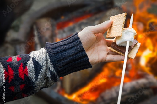 Quadro su tela Closeup of Hands Building Smore with Roasted Marshmallow and Chocolate At Campfi