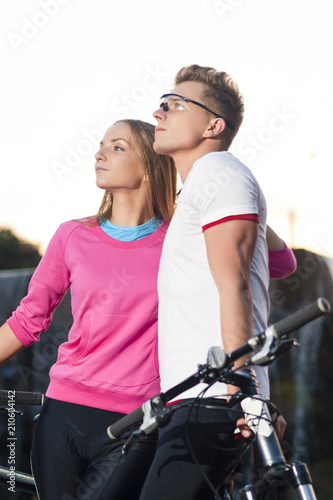 Sport Concepts. Young Caucasian Couple with Mountain Bikes Posing Together Outdoors In Front of Waterfall on The Background
