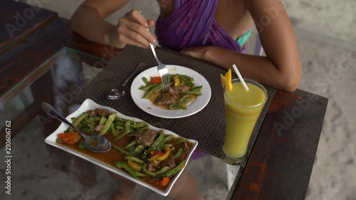 A woman in a restaurant eating meat with vegetables photo