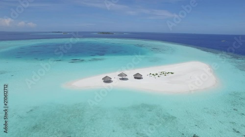 flight over a small tropical sandy island - umbrellas on the sandbank