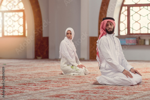 Muslim man and woman praying for Allah in the mosque together