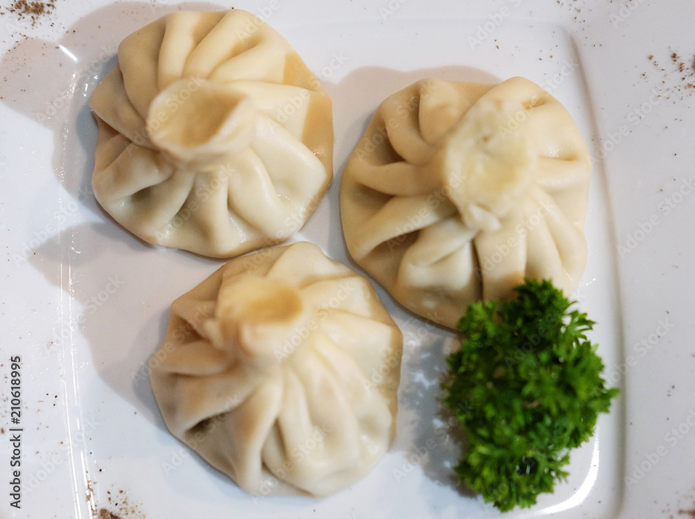 Georgian dumplings Khinkali with meat, greens and tomato spicy sauce. Georgian dumplings Khinkali with meat, greens and tomato spicy sauce.