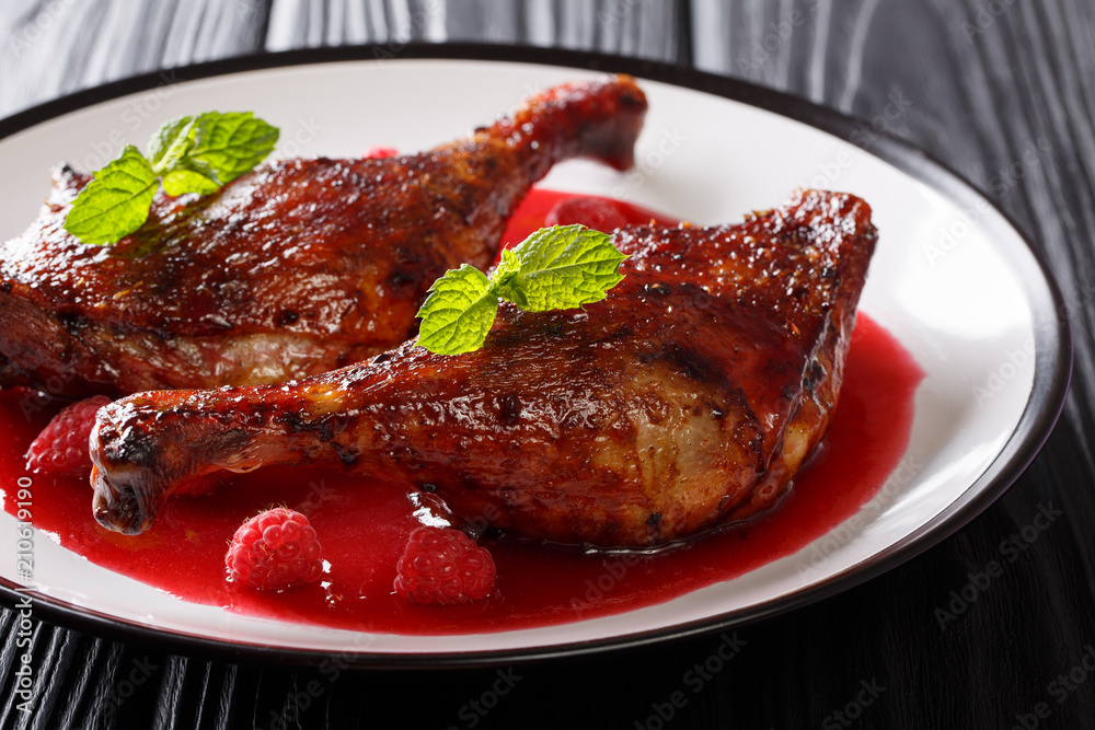 Organic food: fried duck legs served with fresh raspberry sauce and crumpled mint on a plate. horizontal