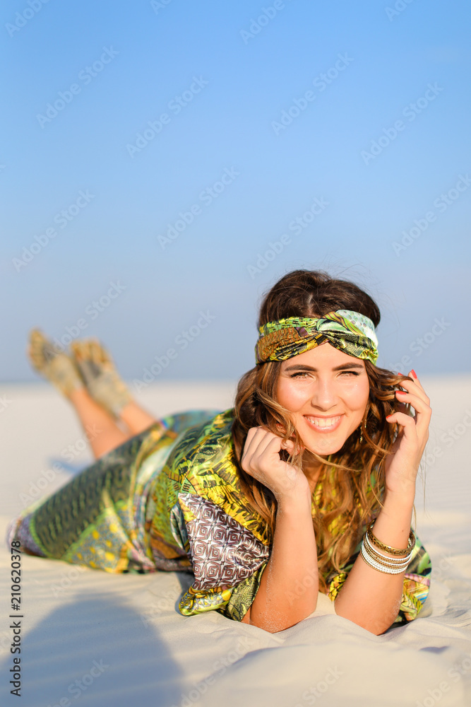 Young smiling woman wearing green beach robe lying on white sand. Concept  of sunbathe and photo session in desert. Stock Photo | Adobe Stock