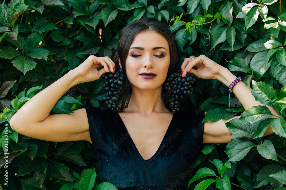 Portrait of young sexy brunette with black grapes. Portrait of young sexy brunette with black grapes.