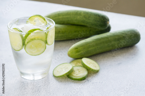Cold water with cucumber and ice in glass on the table